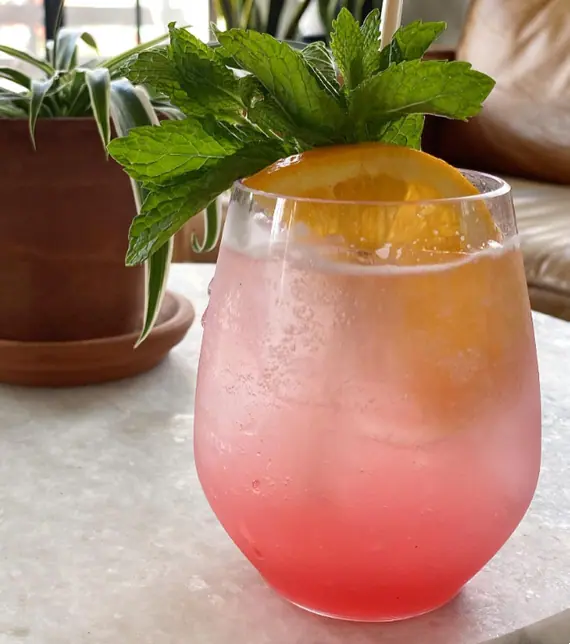 a glass filled with a drink sitting on top of a table