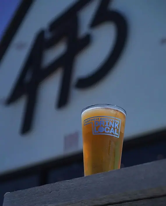 a glass of beer sitting on top of a wooden table
