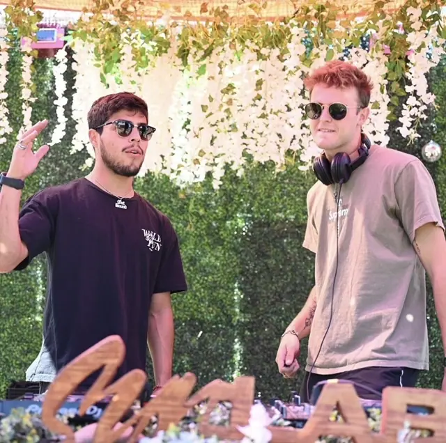 two men standing next to each other in front of a sign
