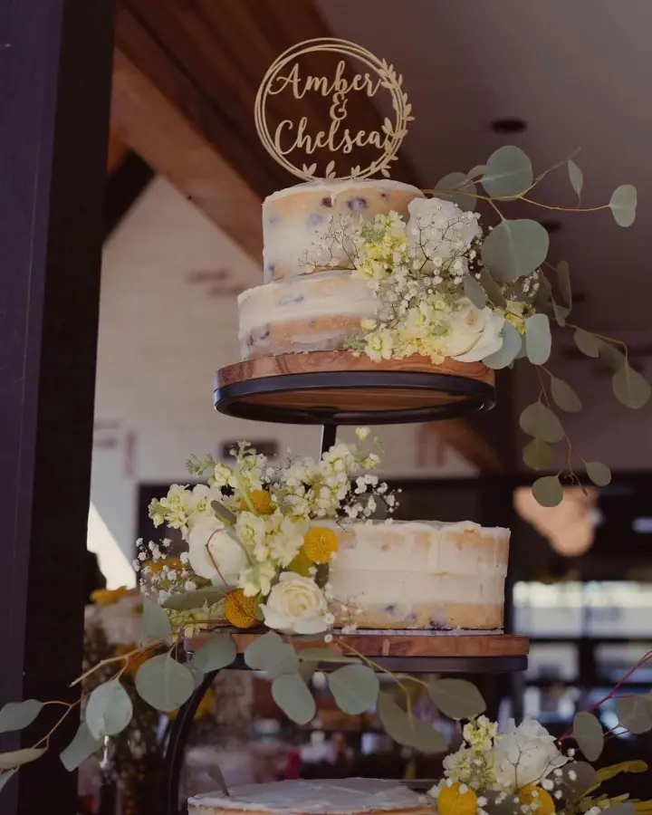 a three tiered cake with flowers and greenery