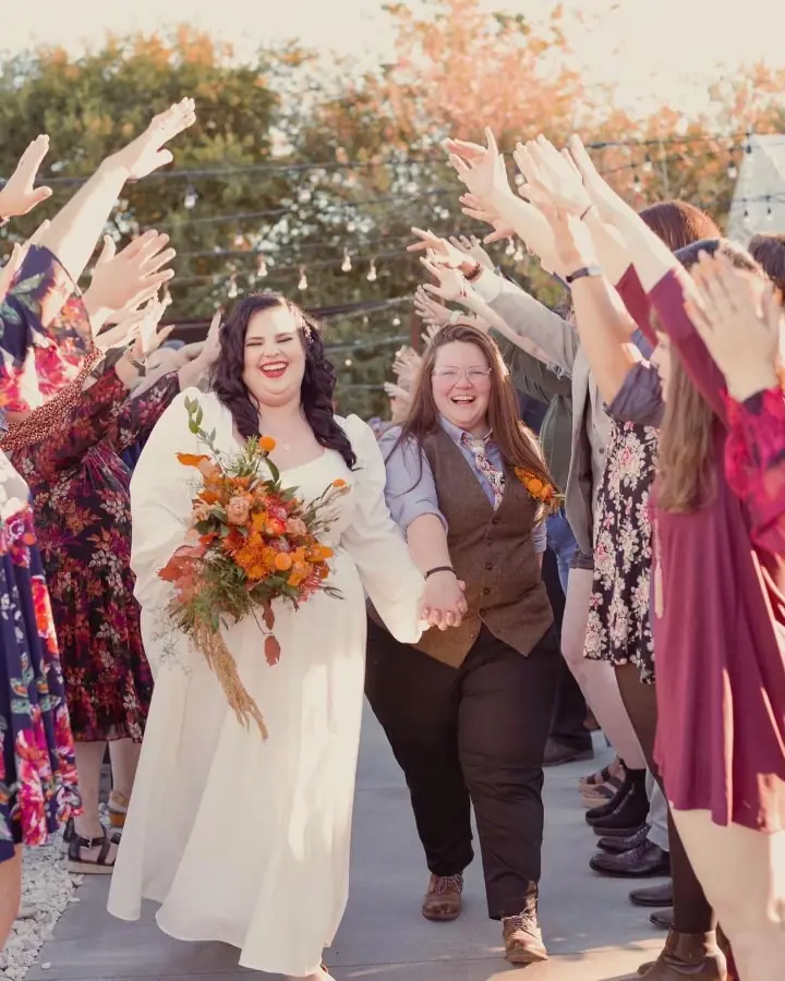 a bride and groom walking through a group of people
